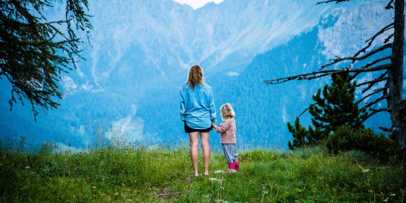 Parent and child looking out at Colorado mountain ridges